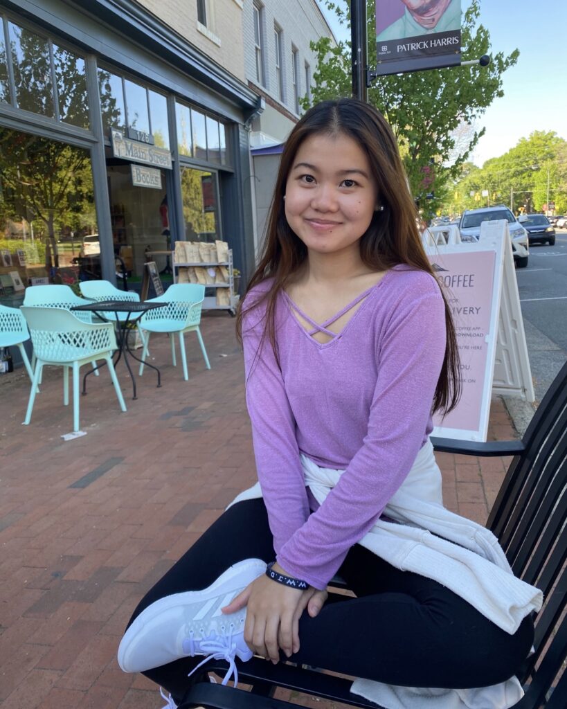 A picture of Taw Meh sitting on a bench in front of Summit Coffee on Main Street during her Davidson College tour in spring of 2021. 