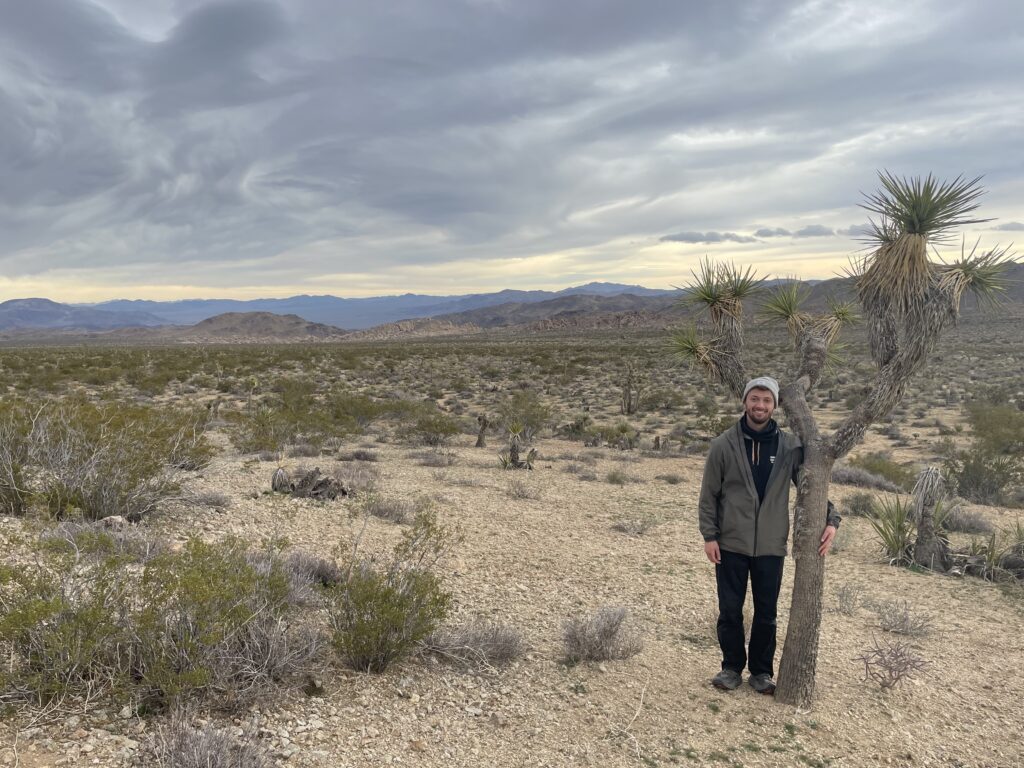 Josh standing next to tree in desert